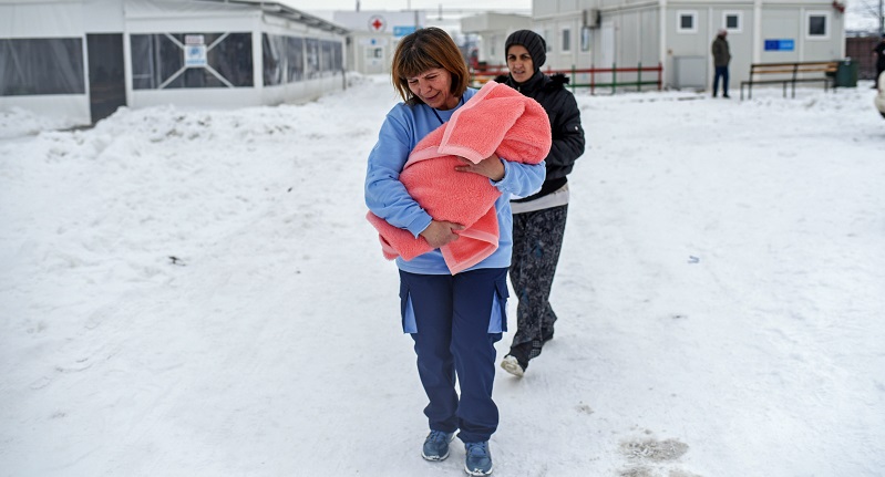 A enfermeira Slagjana Perchinkovska transporta ao colo o pequeno Iliyas que nasceu no campo de refugiados da Macedónia